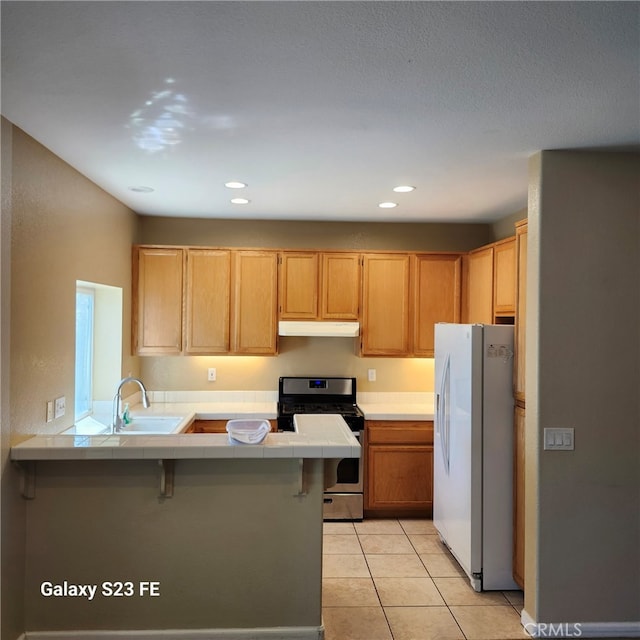 kitchen with sink, kitchen peninsula, white refrigerator with ice dispenser, and gas stove