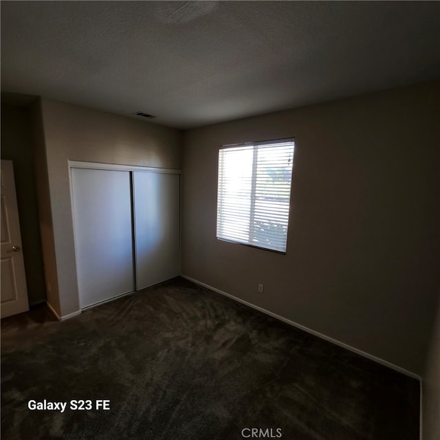 unfurnished bedroom with a closet and dark colored carpet