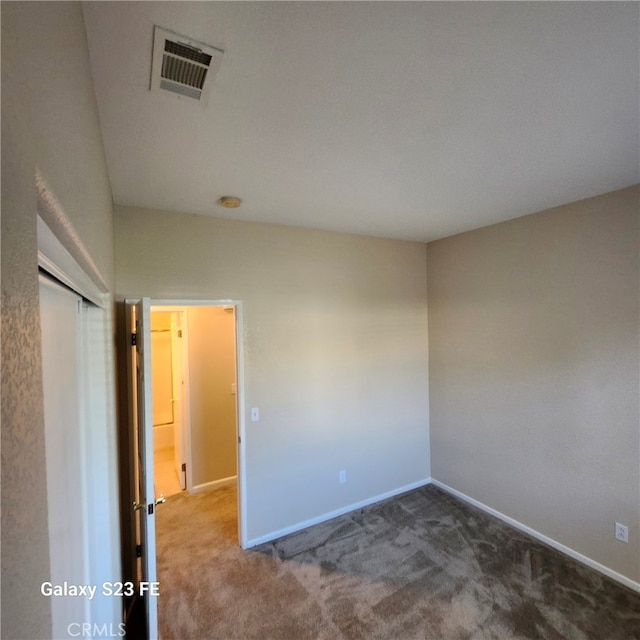 spare room with dark colored carpet