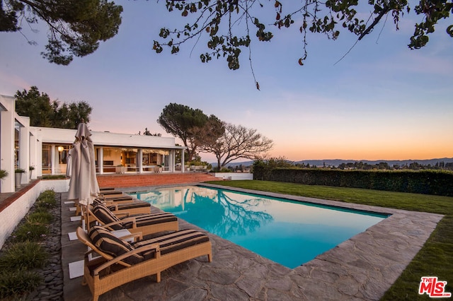 pool at dusk featuring a patio area