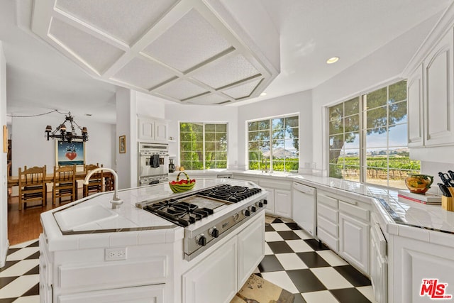 kitchen featuring appliances with stainless steel finishes, white cabinetry, a kitchen island, tile countertops, and sink