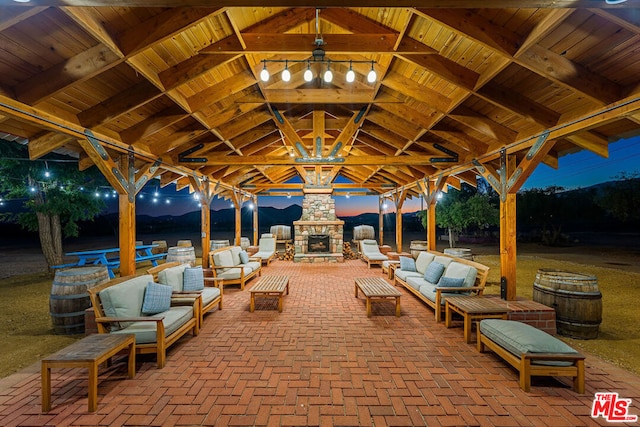 view of patio with an outdoor living space with a fireplace and a gazebo