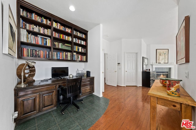 office area featuring a tiled fireplace and dark hardwood / wood-style floors