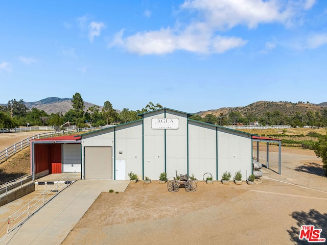 view of outdoor structure featuring a mountain view, a garage, and a rural view