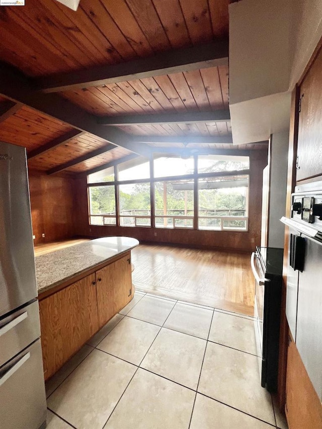 kitchen featuring stainless steel fridge, light stone counters, wood ceiling, light hardwood / wood-style flooring, and vaulted ceiling with beams