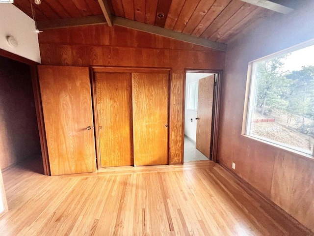 unfurnished bedroom featuring lofted ceiling with beams, light wood-type flooring, wood ceiling, and a closet