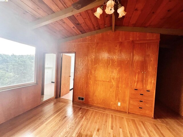 unfurnished bedroom with vaulted ceiling with beams, wooden walls, wood-type flooring, and wooden ceiling