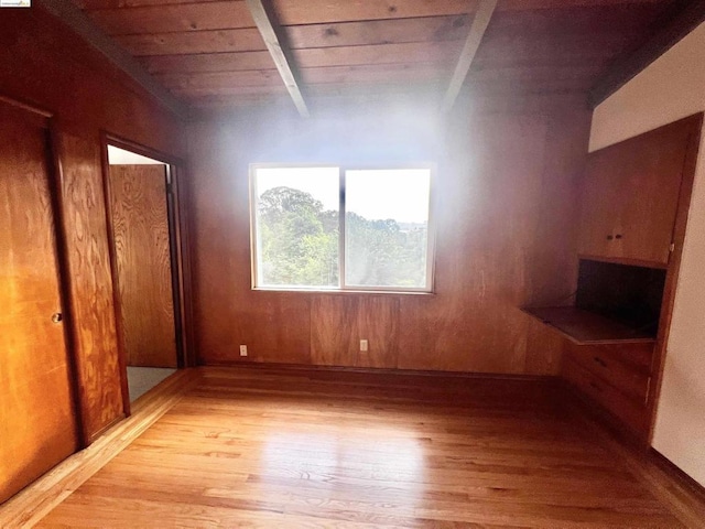 unfurnished bedroom featuring wood walls, beam ceiling, wooden ceiling, and light hardwood / wood-style flooring