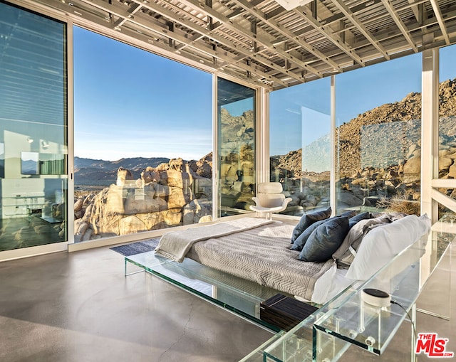 bedroom with a wall of windows, concrete flooring, and a mountain view