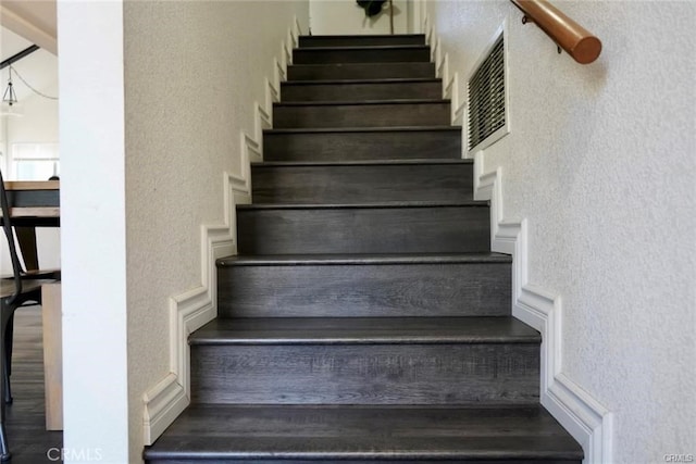 stairs featuring a notable chandelier and hardwood / wood-style floors