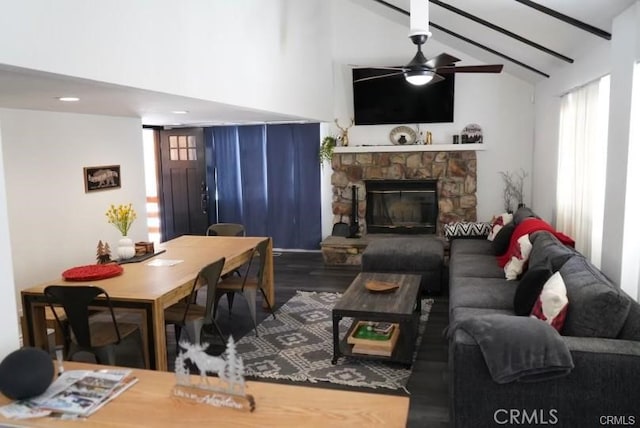 living room with vaulted ceiling with beams, a fireplace, ceiling fan, and dark wood-type flooring