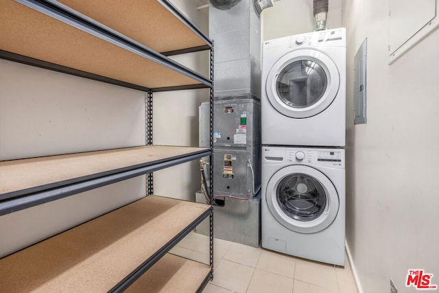 washroom with stacked washer and dryer, electric panel, and light tile patterned flooring