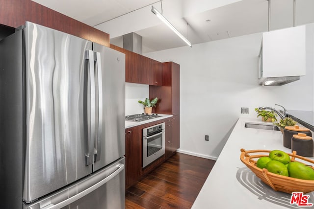 kitchen featuring appliances with stainless steel finishes, sink, and dark hardwood / wood-style flooring