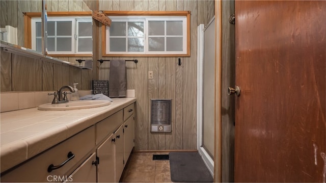 bathroom featuring vanity, wood walls, tile patterned flooring, and a shower with door