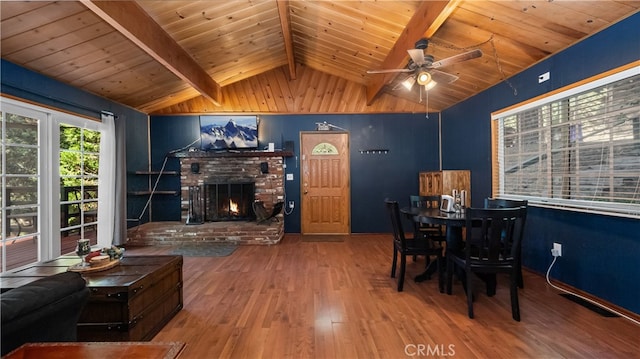 dining space with wood ceiling, lofted ceiling with beams, hardwood / wood-style flooring, a brick fireplace, and ceiling fan