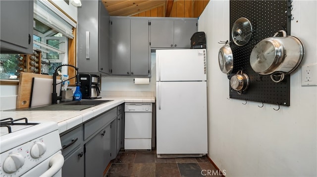 kitchen with lofted ceiling, white appliances, tile counters, and gray cabinets