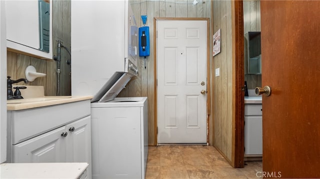 clothes washing area featuring stacked washer and dryer, wood walls, and sink