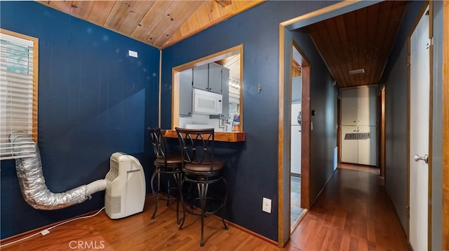 hall featuring vaulted ceiling, wooden ceiling, and hardwood / wood-style floors