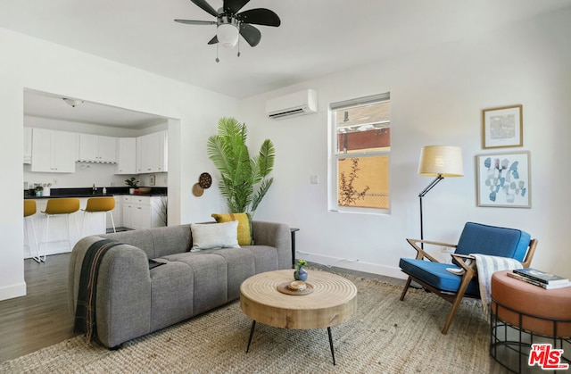 living room featuring an AC wall unit, ceiling fan, sink, and wood-type flooring