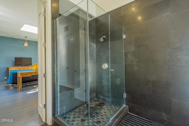 bathroom featuring hardwood / wood-style floors, a skylight, and walk in shower