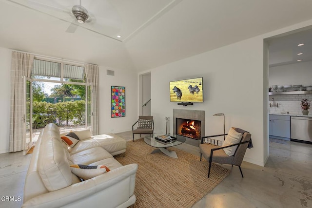 living room with a tile fireplace, vaulted ceiling, and ceiling fan