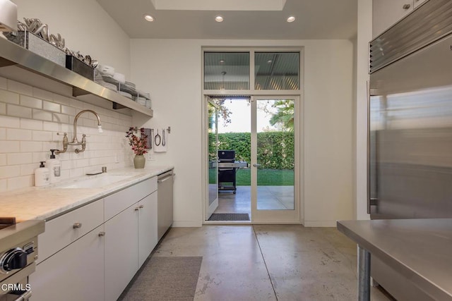 kitchen featuring sink, appliances with stainless steel finishes, white cabinetry, backsplash, and light stone counters