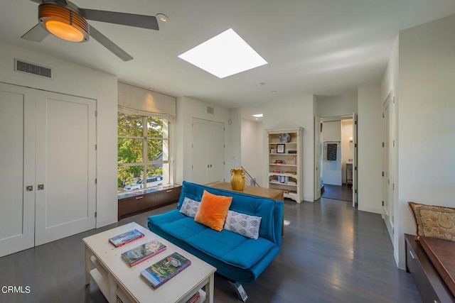 living room with dark hardwood / wood-style floors, ceiling fan, and a skylight