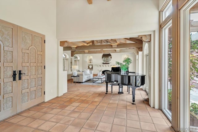 tiled entrance foyer with french doors, a towering ceiling, and beam ceiling