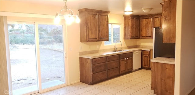 kitchen with white dishwasher, hanging light fixtures, light tile patterned floors, sink, and an inviting chandelier