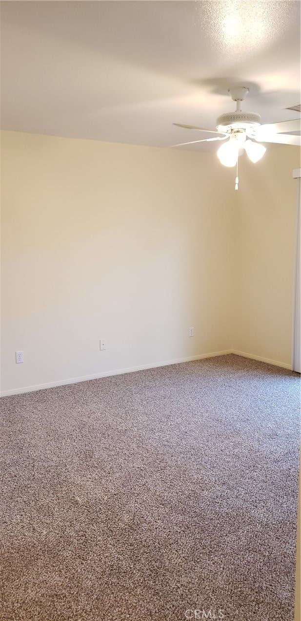 carpeted spare room featuring a textured ceiling and ceiling fan