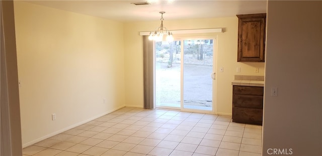 unfurnished dining area with light tile patterned floors and a notable chandelier