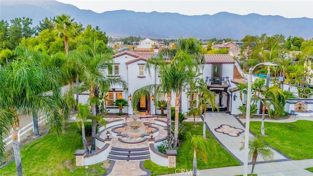 view of front of house with a balcony, a mountain view, and a front yard