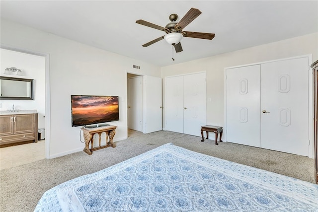 bedroom featuring light carpet, multiple closets, ceiling fan, and sink