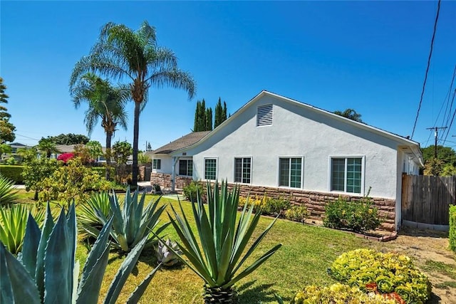 1021 S Lark Ellen Ave, West Covina, CA 91791 - view of side of home with stucco siding, stone siding, fence, and a lawn