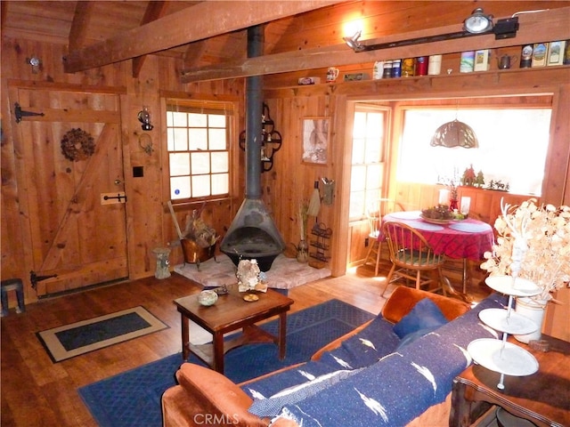 living room featuring hardwood / wood-style flooring, lofted ceiling with beams, a wood stove, and a wealth of natural light