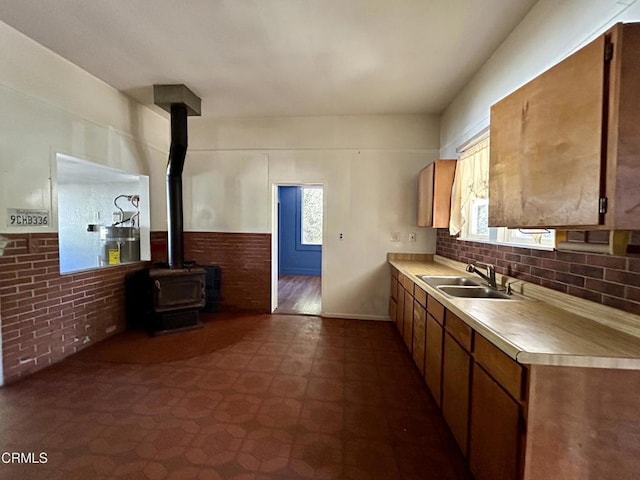 kitchen featuring brick wall, a healthy amount of sunlight, a wood stove, and sink