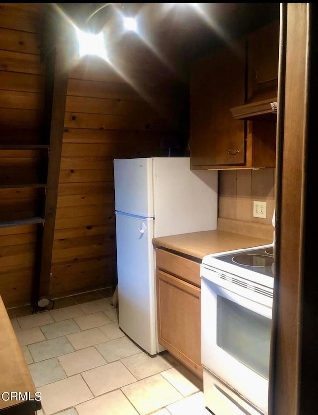 kitchen featuring white appliances, light tile patterned floors, and wooden walls