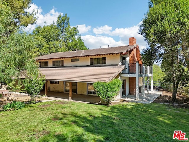 rear view of property featuring a balcony, a lawn, and a patio