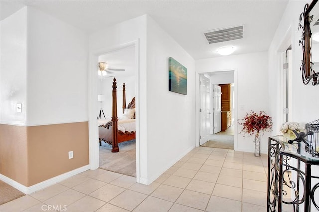 hall with light tile patterned floors, baseboards, visible vents, and light carpet