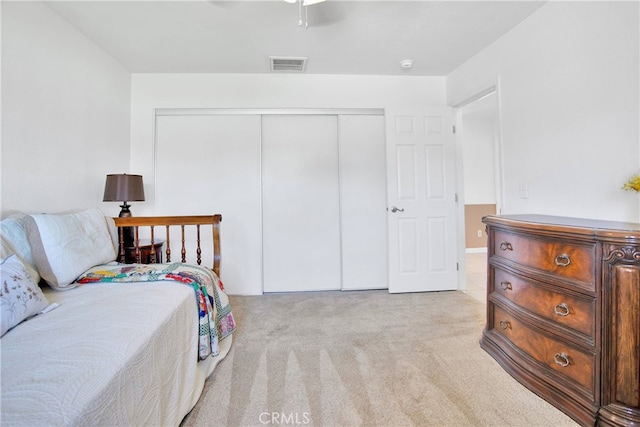 bedroom featuring visible vents, light carpet, a closet, and ceiling fan