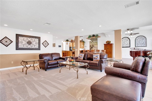 living room with ceiling fan, a textured ceiling, and light carpet