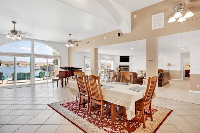 dining area with a water view, light tile patterned flooring, and ceiling fan