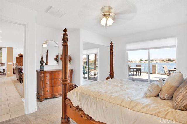 tiled bedroom featuring ceiling fan, access to exterior, and a water view