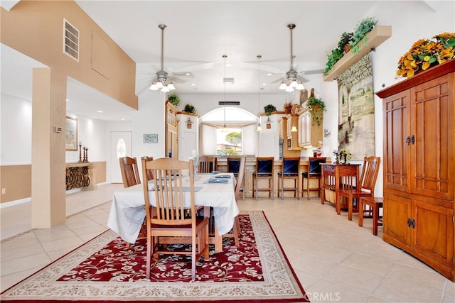 dining space featuring ceiling fan, light tile patterned floors, and a high ceiling