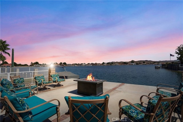 patio terrace at dusk with a water view and an outdoor fire pit