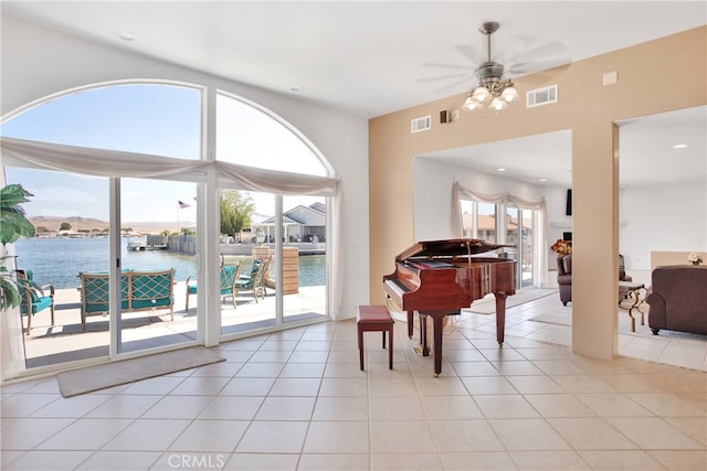 misc room with ceiling fan, light tile patterned floors, and a water view