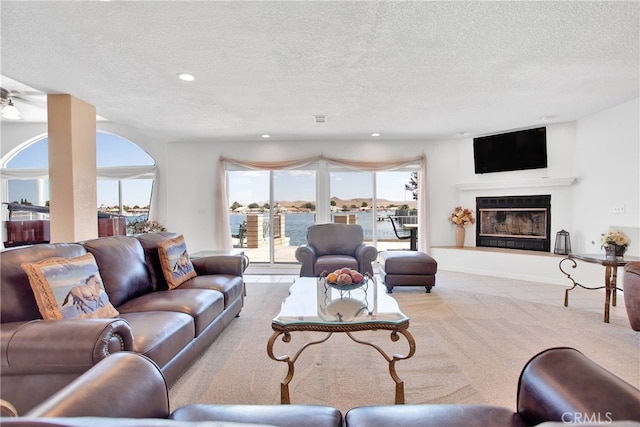 living room featuring a textured ceiling, ceiling fan, and light carpet