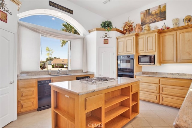 kitchen featuring light stone counters, a center island, light tile patterned flooring, sink, and black appliances