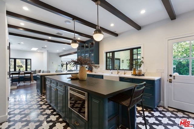 kitchen with a healthy amount of sunlight, decorative light fixtures, a center island, and beverage cooler