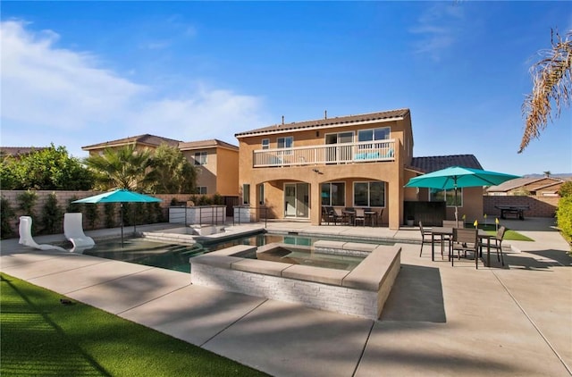 back of house with a patio area, a swimming pool with hot tub, and a balcony